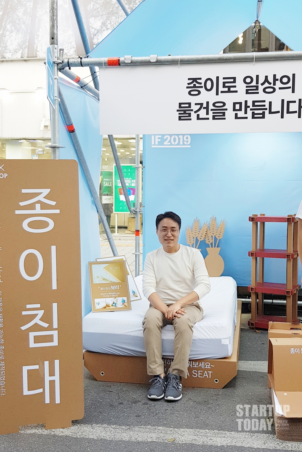 페이퍼팝 박대희 대표가 종이침대 위에 앉아 있다. 종이침대는 300kg 하중까지 거뜬하게 견딜 수 있다. (출처: 스타트업투데이)
